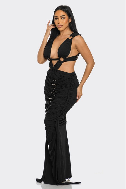 Woman wearing a black backless evening gown with cut-out design on a white background