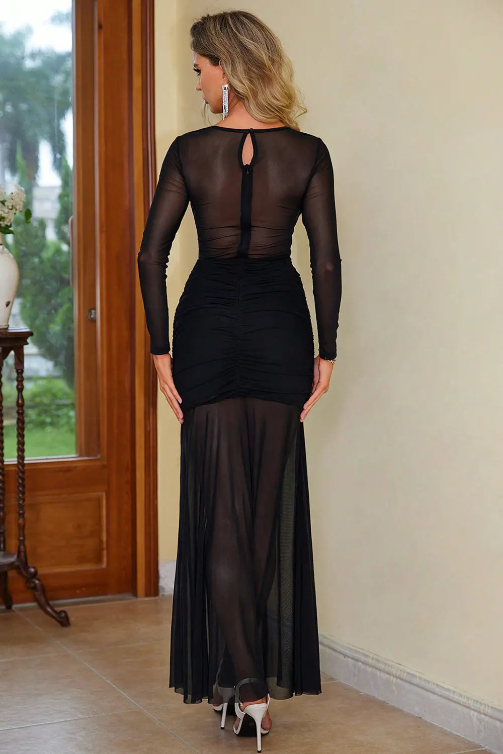 Model in semi-sheer black slit round neck dress with sculpted fit back view