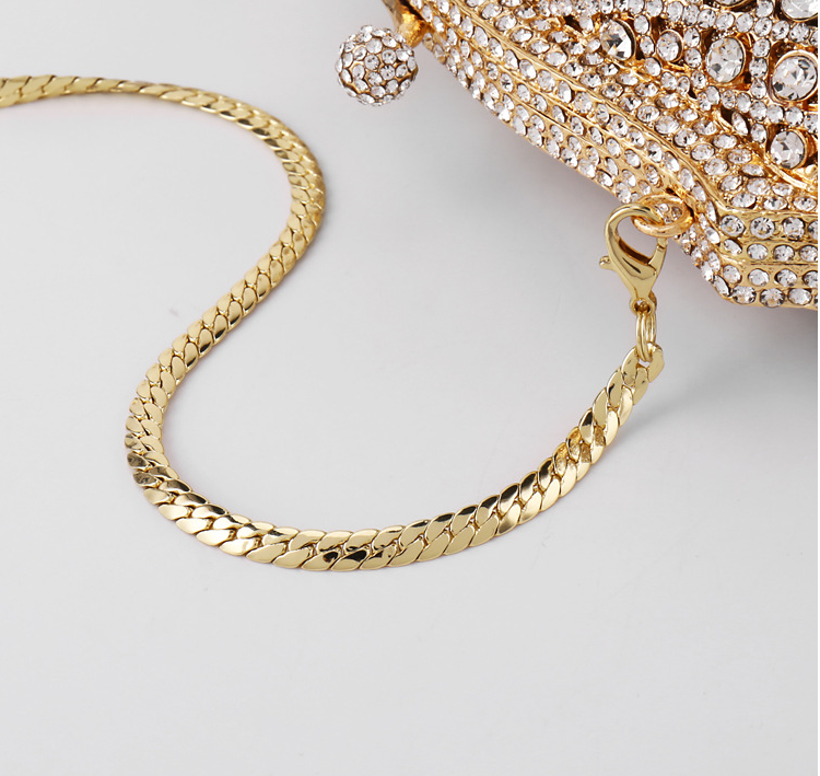 Elegant gold clutch with structured design and clasp top chain strap close on on white background