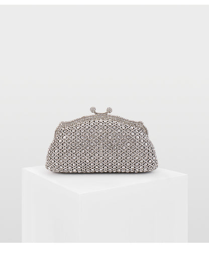 Silver rhinestone clutch bag with vintage kiss-lock closure on a white column