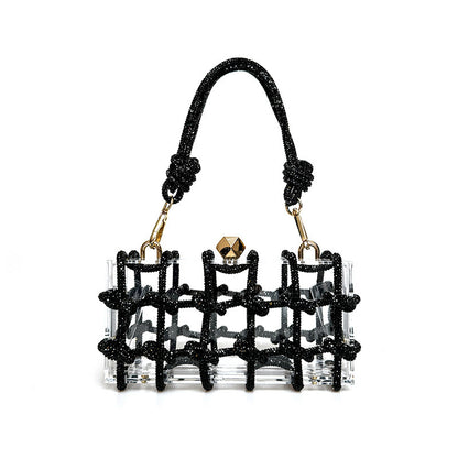 A shiny black rhinestone-encrusted acrylic clear handbag in a square shape with a single handle and gold-colored hardware.