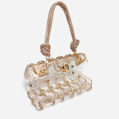 A champagne shiny rhinestone-encrusted acrylic handbag in a square shape with a single shoulder strap and gold-colored hardware.