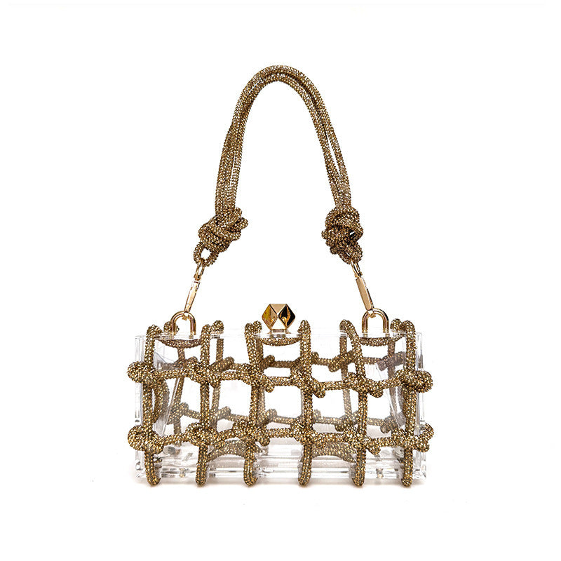 A shiny gold rhinestone-encrusted acrylic clear handbag in a square shape with a single shoulder strap and gold-colored hardware.