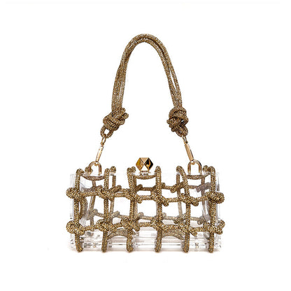 A shiny gold rhinestone-encrusted acrylic clear handbag in a square shape with a single shoulder strap and gold-colored hardware.