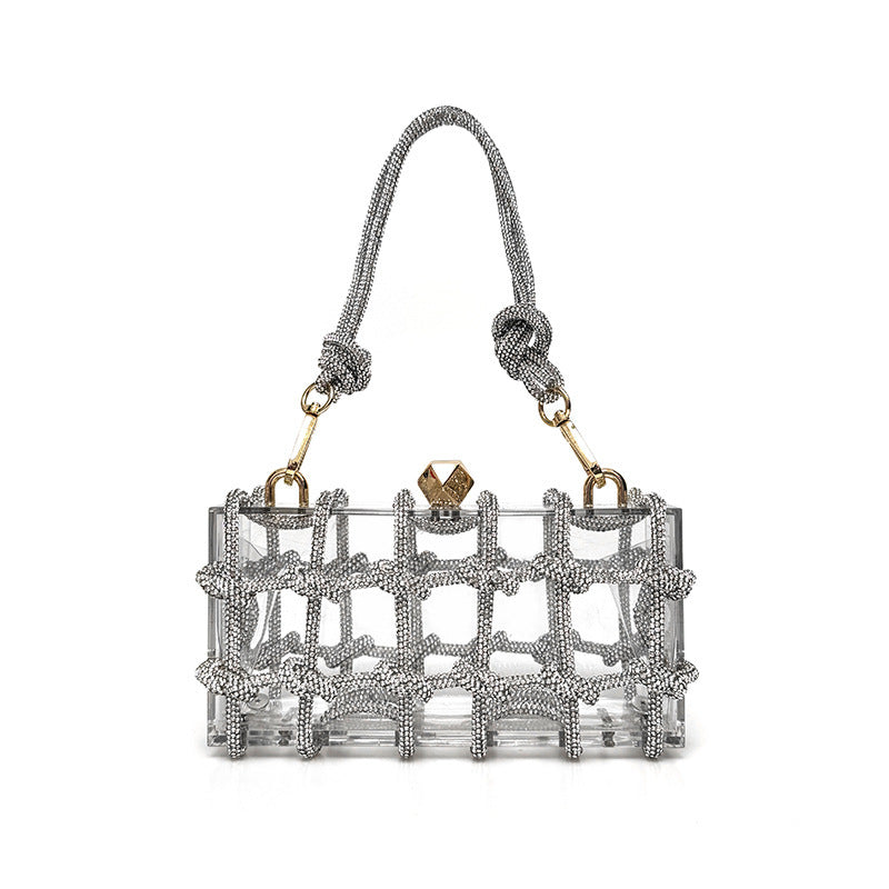 A shiny silver rhinestone-encrusted acrylic clear handbag in a square shape with a single handle and gold-colored hardware.