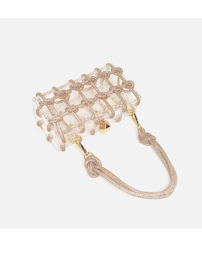 Flat lay of shiny rhinestone-encrusted champagne acrylic handbag in a square shape with a single handle and gold-colored hardware.