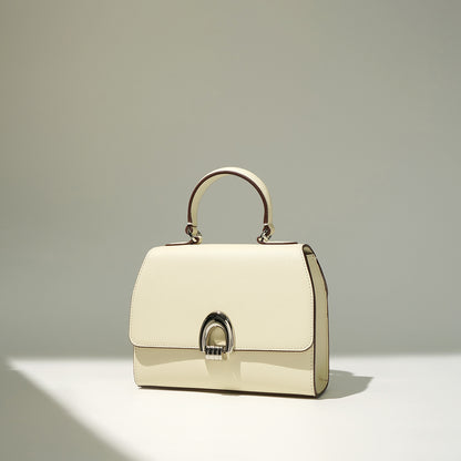An ivory/white colored handbag with a shell shape, made from genuine leather, featuring a sandwich pocket design and a single handle strap.