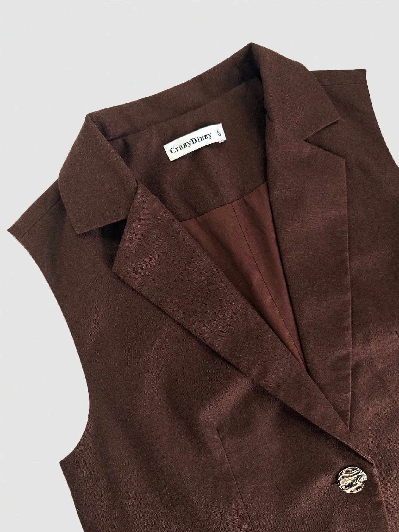 Brown vest neckline close up of two piece pant suit set on a white background