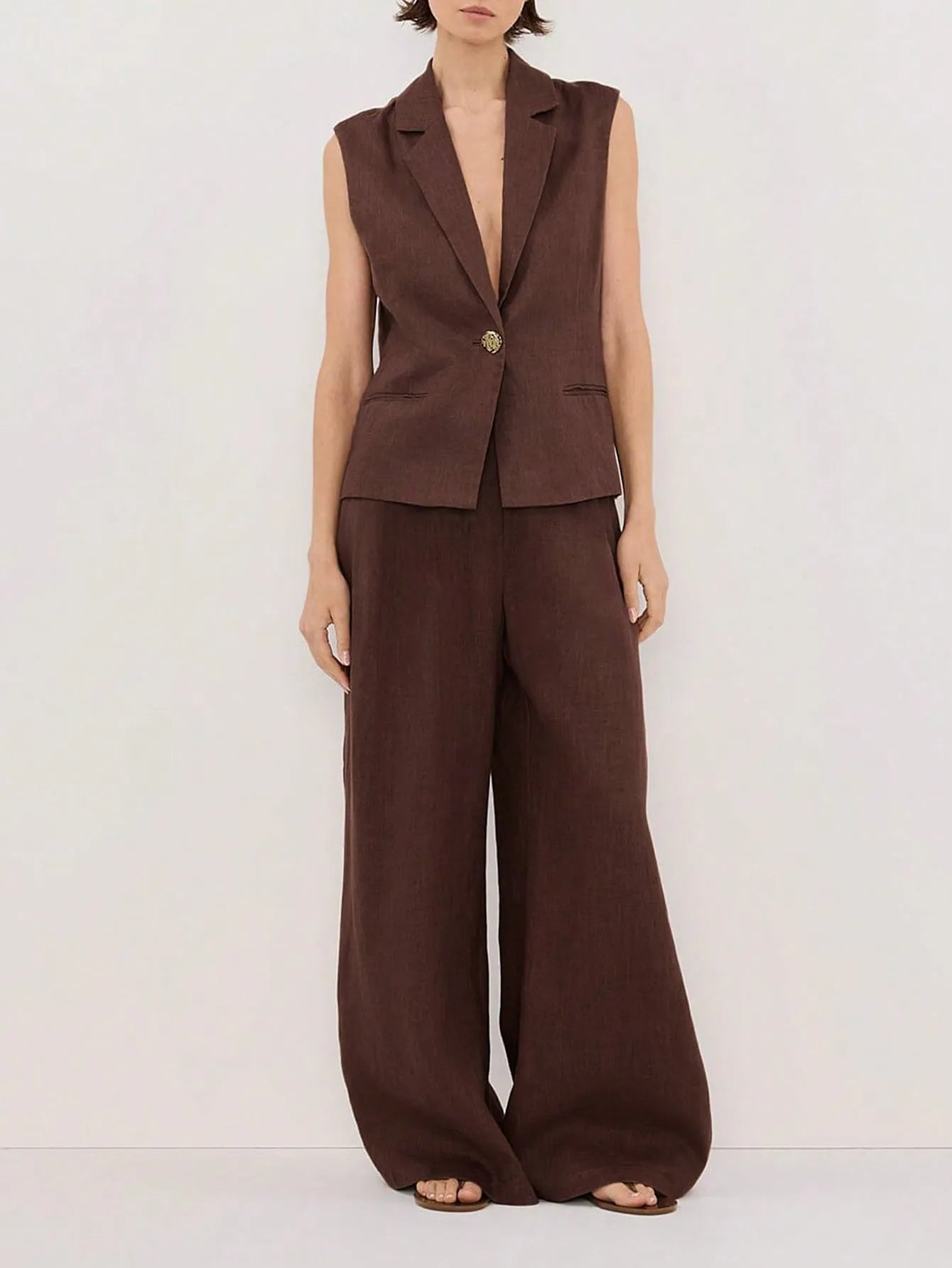 woman wearing brown sleeveless blazer and wide-leg pants two piece set on a white background