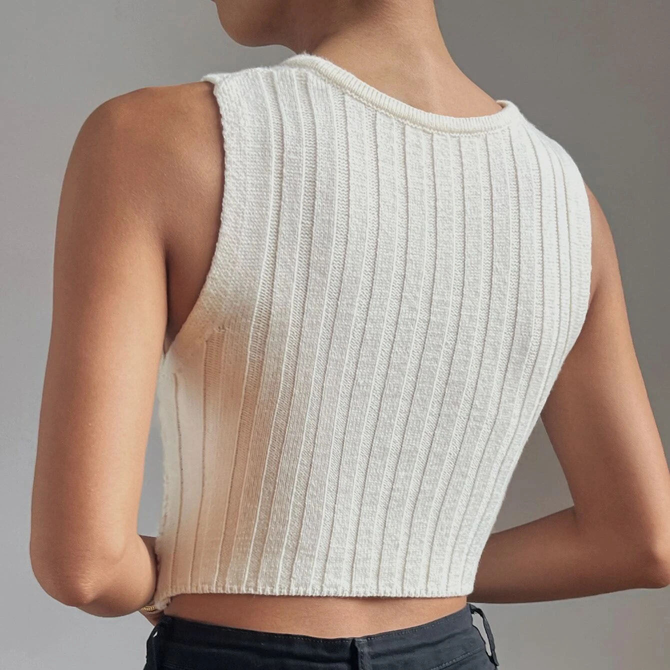 back view of women wearing a sleeveless cropped knit top with chain neck detail