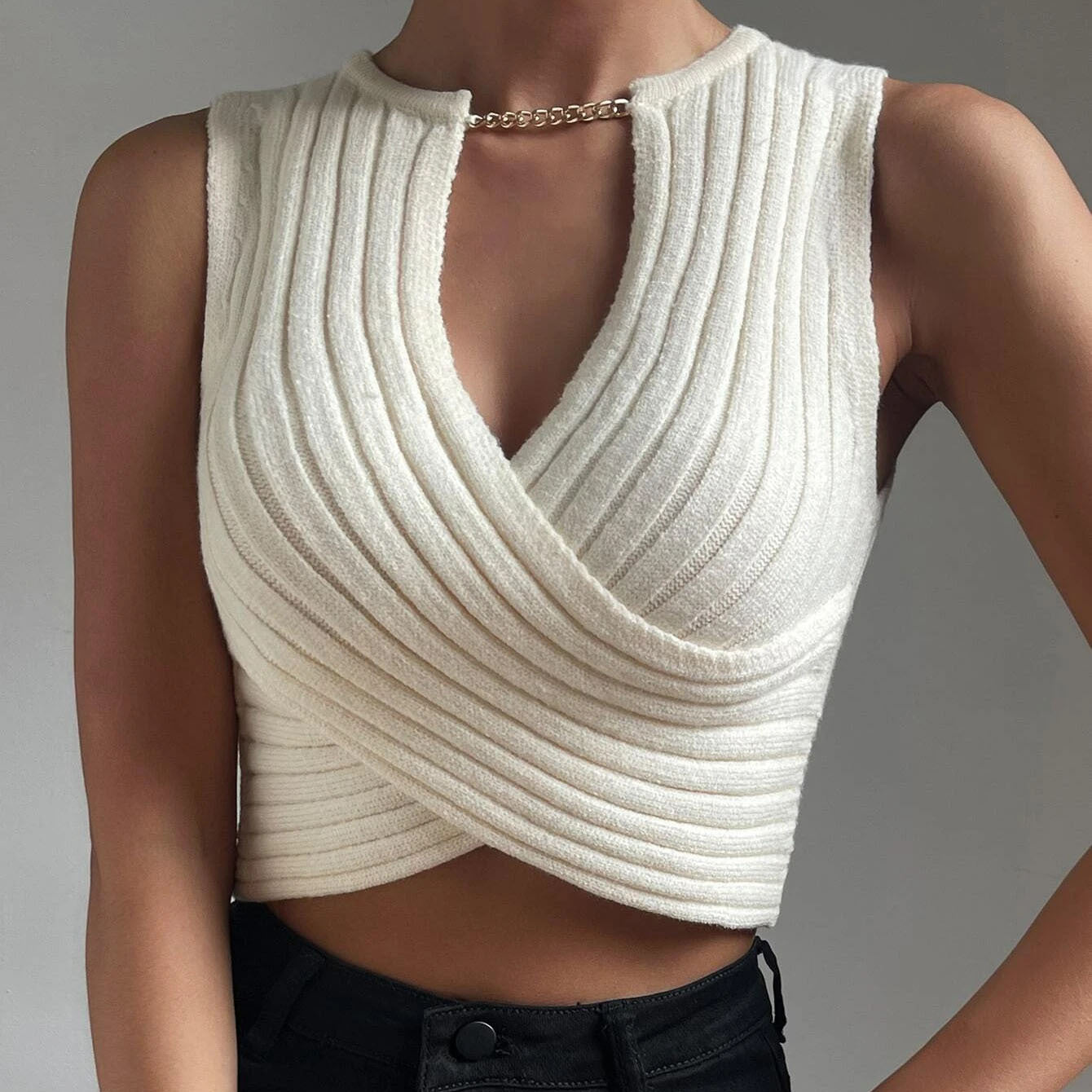 Women wearing a cropped sleeveless cutout knit top with chain neck detail