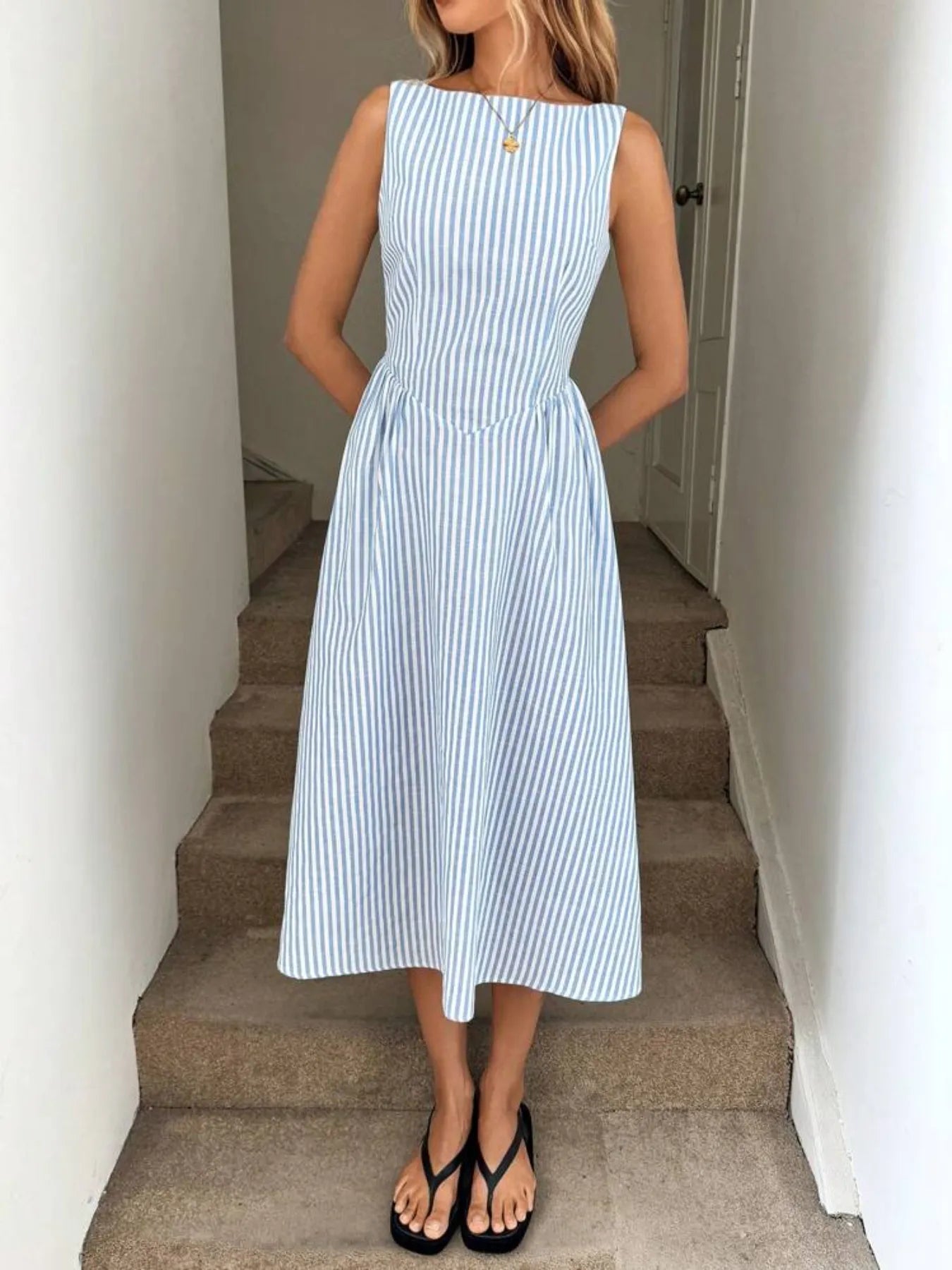 Woman wearing a blue and white striped midi dress standing on a staircase.