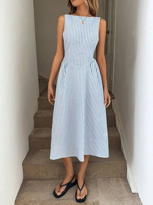 Woman wearing a blue and white striped casual resort style dress standing on a staircase.