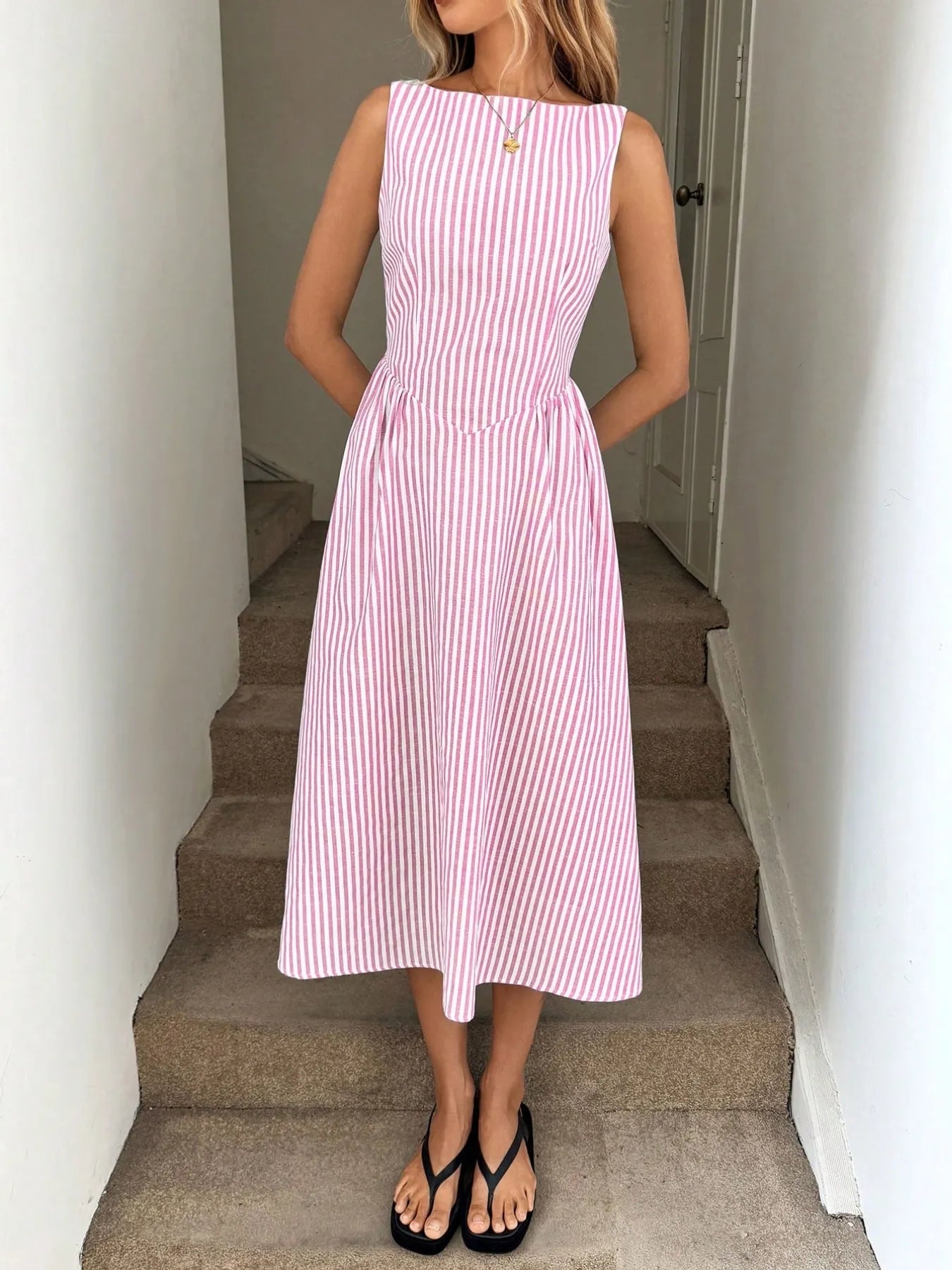 Woman wearing pink sleeveless striped midi dress outdoors