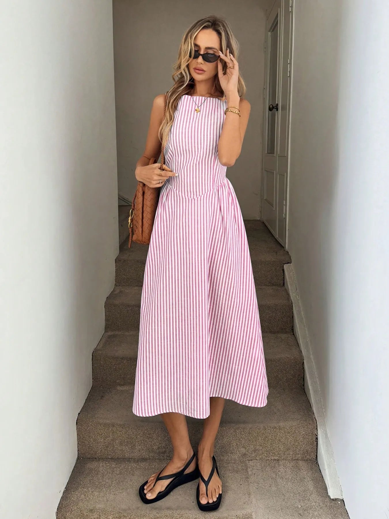 front view of casual pink striped midi summer dress on woman holding a shoulder bag