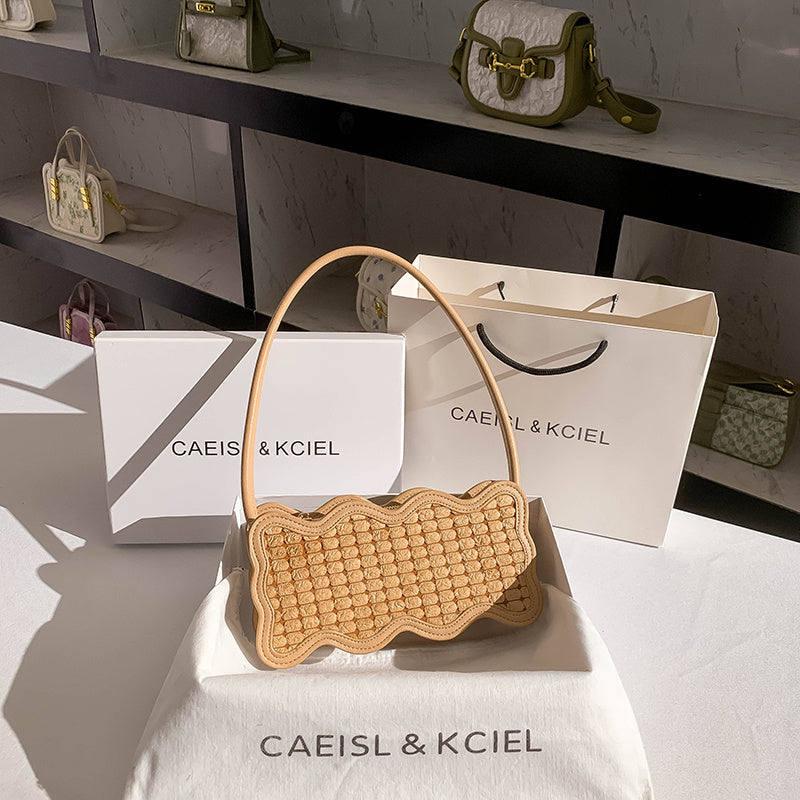 Woven scalloped textured Leather handbag on a white surface with 'CAEISL & KCIEL' branding.