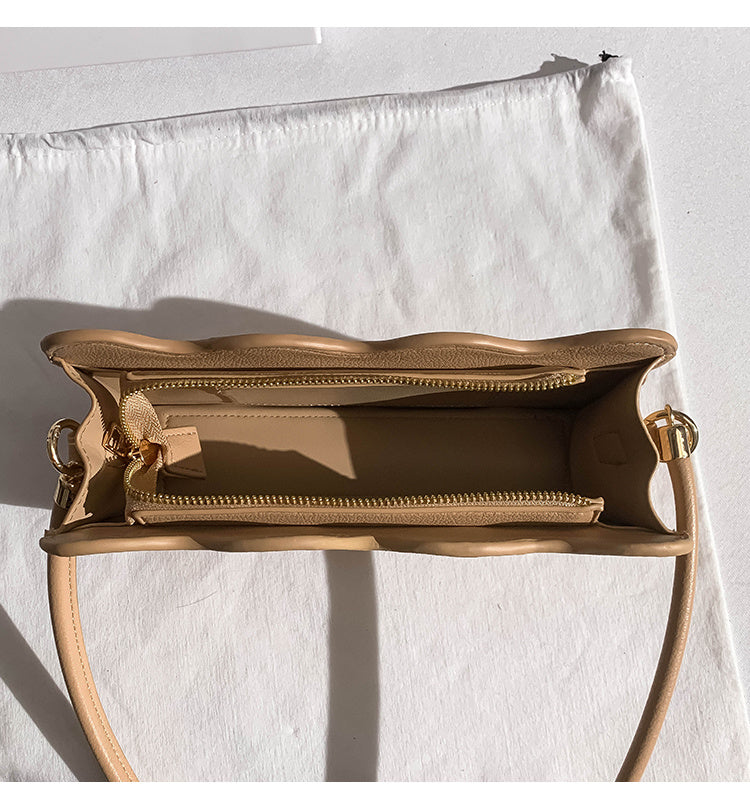 beige handbag with a detachable  strap on a light background