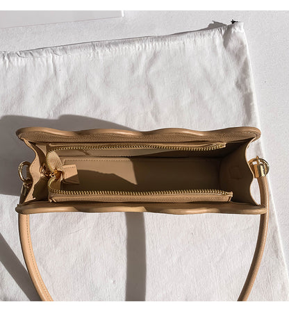beige handbag with a detachable  strap on a light background