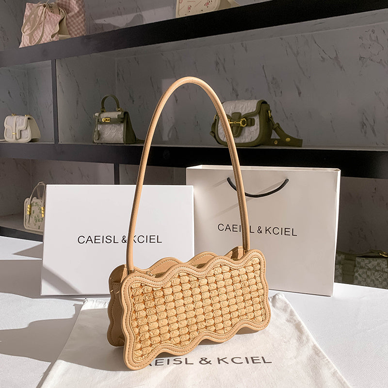 Woven handbag on a white surface with 'CAEISL & KCIEL' branding.