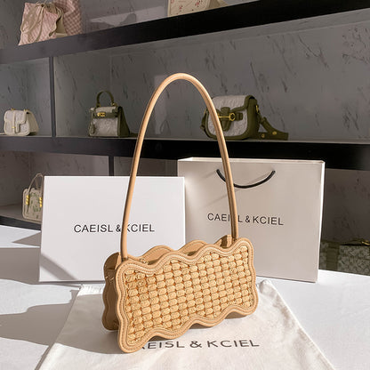 Woven handbag on a white surface with 'CAEISL & KCIEL' branding.