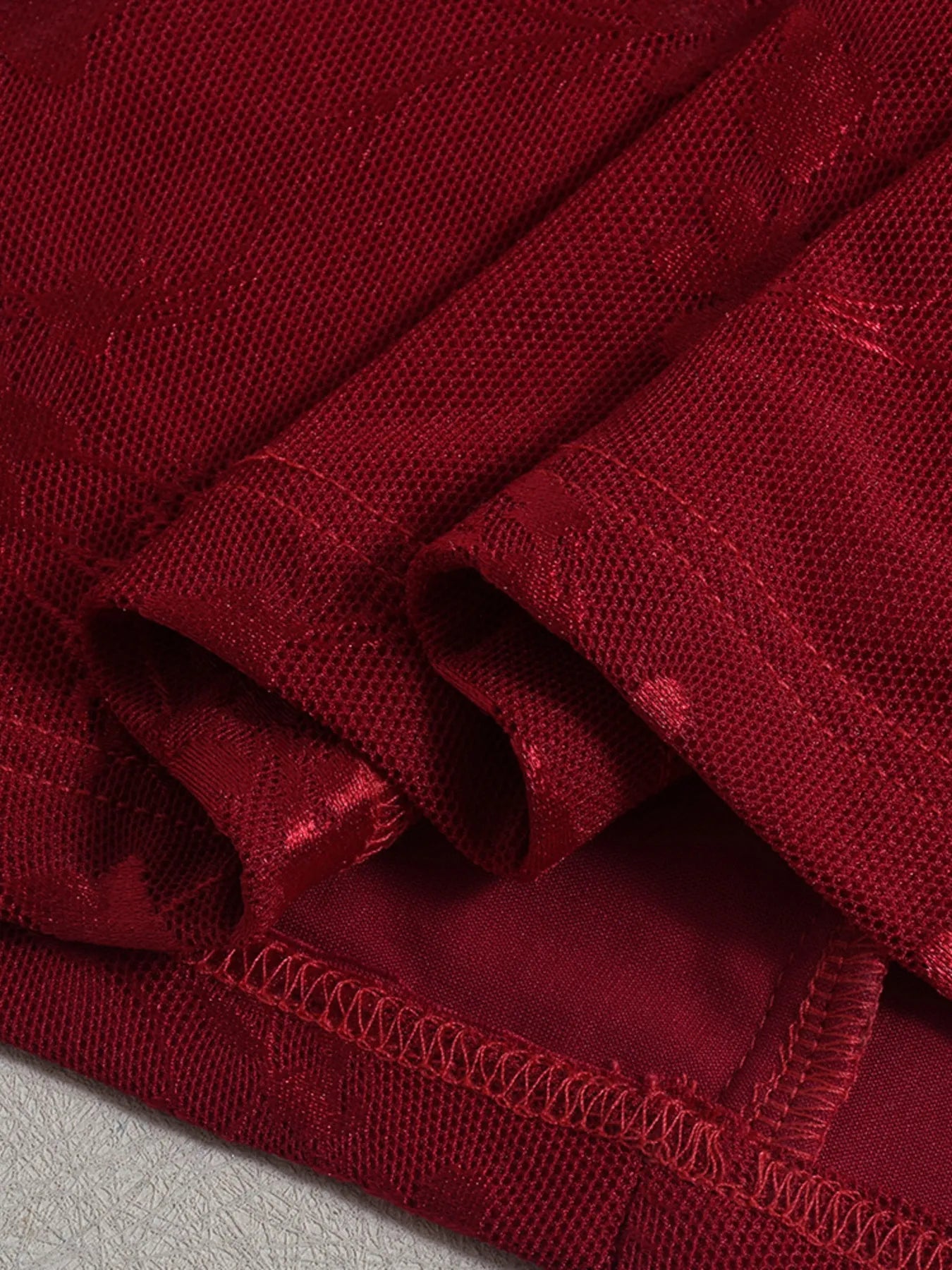 Close-up of a hem for Sweetheart Neck Draped Off-Shoulder Bodycon Dress with visible stitching on a gray background