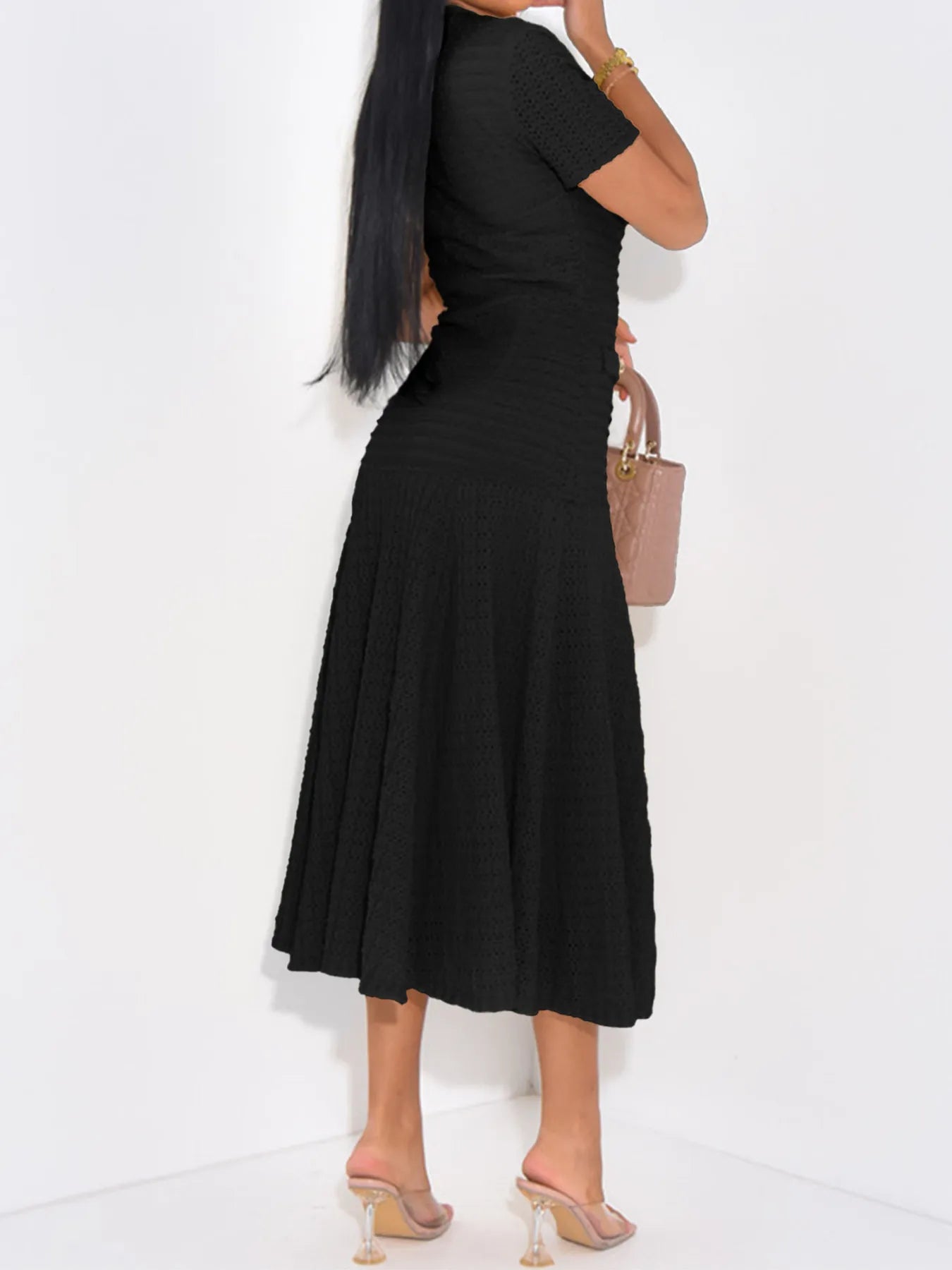 Side view of woman wearing a black ribbed bodycon stretch midi dress on a white background