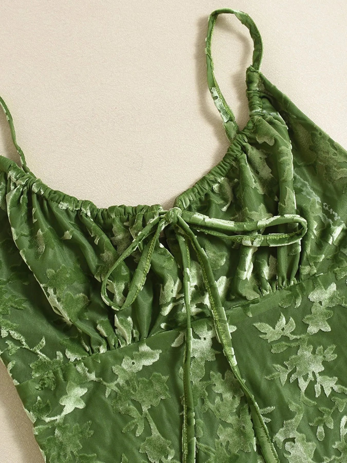 Green floral textured midi summer dress with thin straps on a beige background
