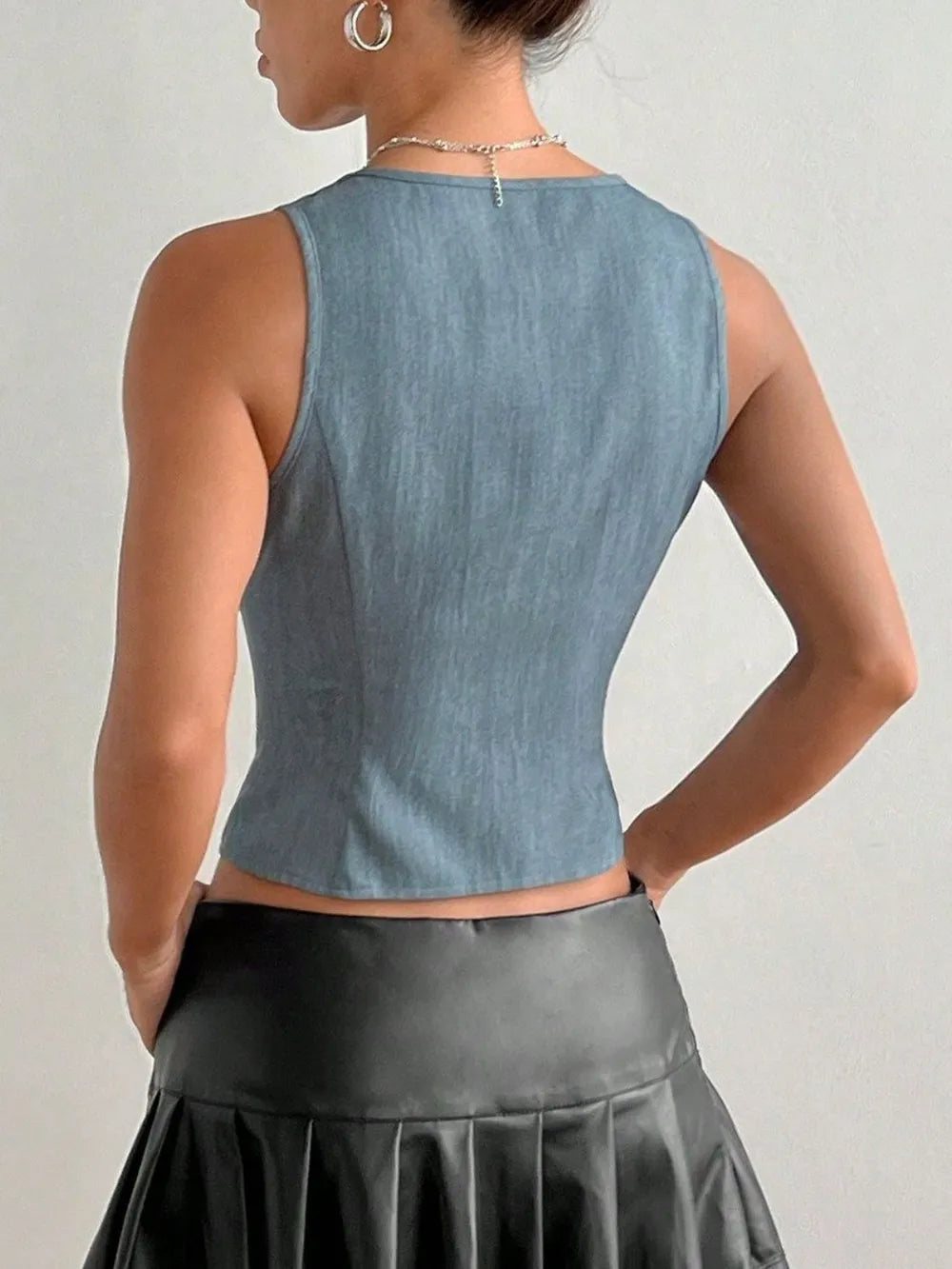 back view of woman wearing a blue  Tied Front V‑Neck Cropped Tank top and black leather skirt on a plain background