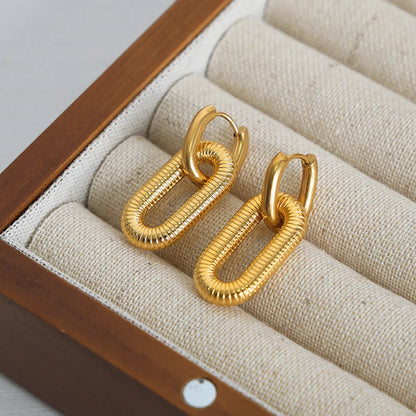 18K Gold plated dangle hypoallergenic earrings on a textured beige surface inside a wooden jewelry box.