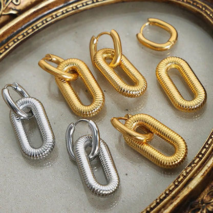 Gold and silver hoop titanium steel hypoallergenic dangle earrings on a textured surface with decorative frame.