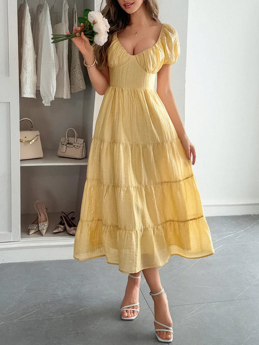 Woman wearing a yellow V-Neck Midi Dress with Short Sleeves holding flowers in a room with shelves and shoes.