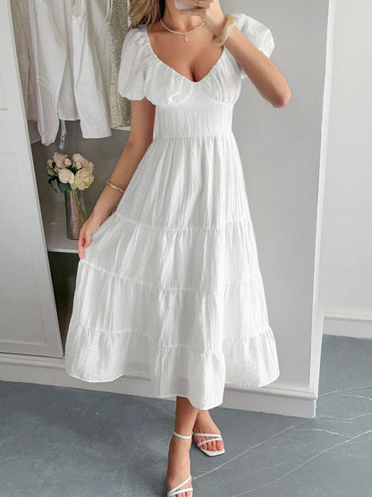 Woman wearing a white V-Neck Midi Dress with Short Sleeves in a minimal indoor setting