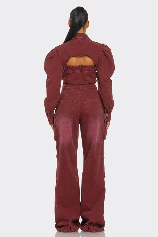 Woman wearing vintage-inspired utility burgundy jumpsuit with front button closure, with puff shoulders, cutouts, cargo flair back view