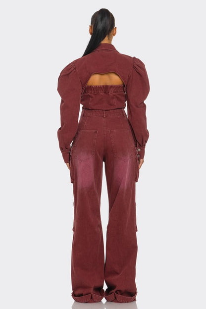 Woman wearing vintage-inspired utility burgundy jumpsuit with front button closure, with puff shoulders, cutouts, cargo flair back view