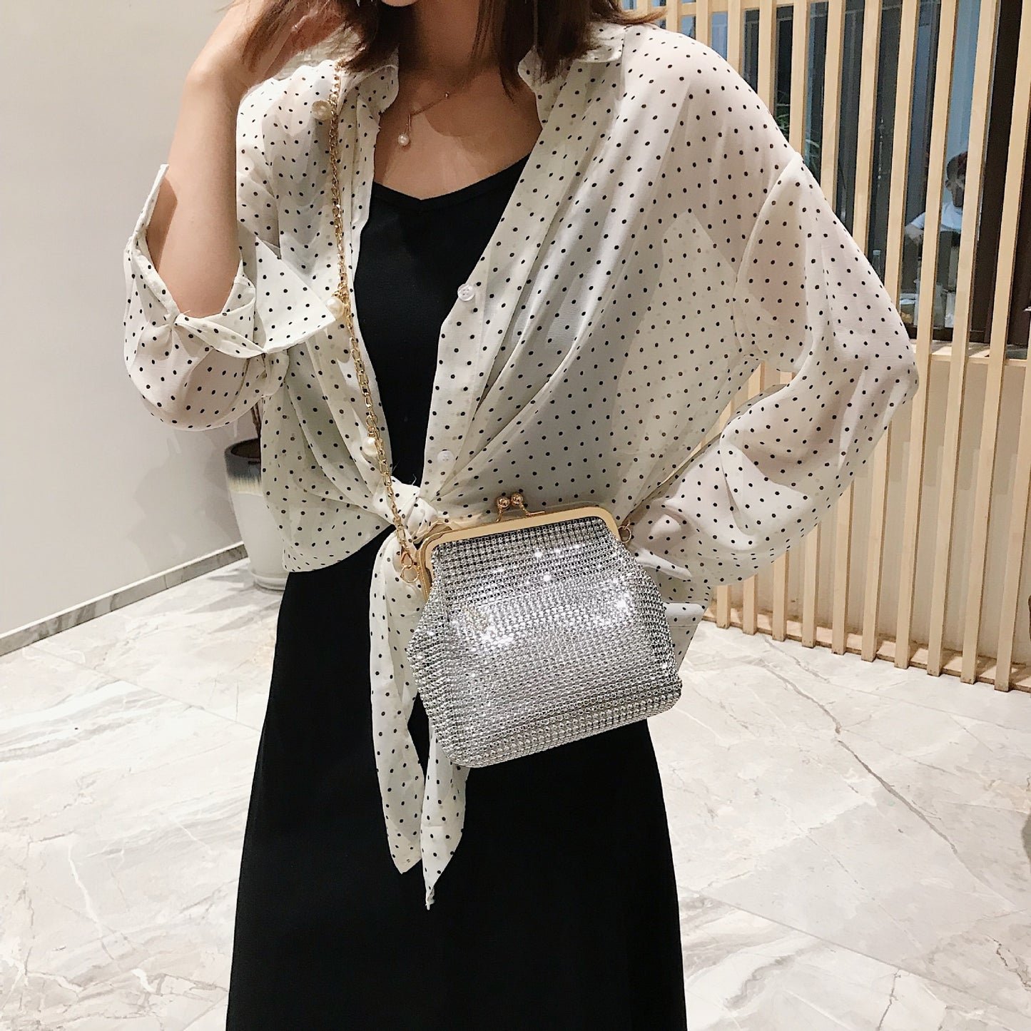 Woman wearing silver rhinestone evening bag with gold pearl chain strap crossbody style