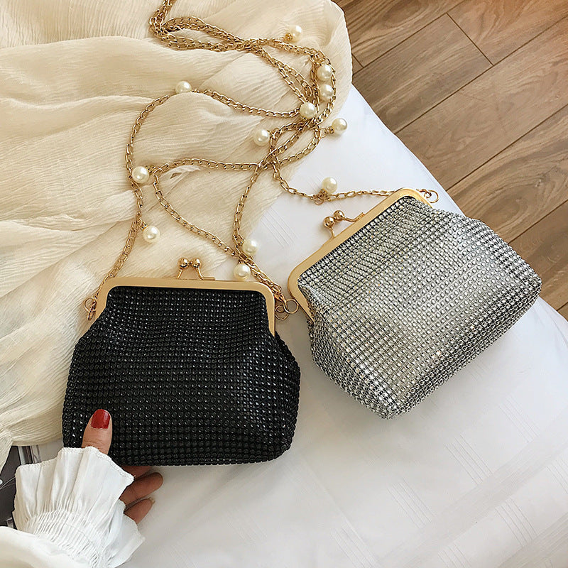 Black and silver rhinestone purses on bed with elegant gold chain straps