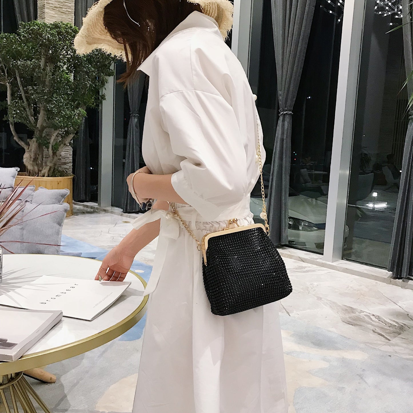 Woman wearing black rhinestone evening bag with gold pearl chain strap crossbody style