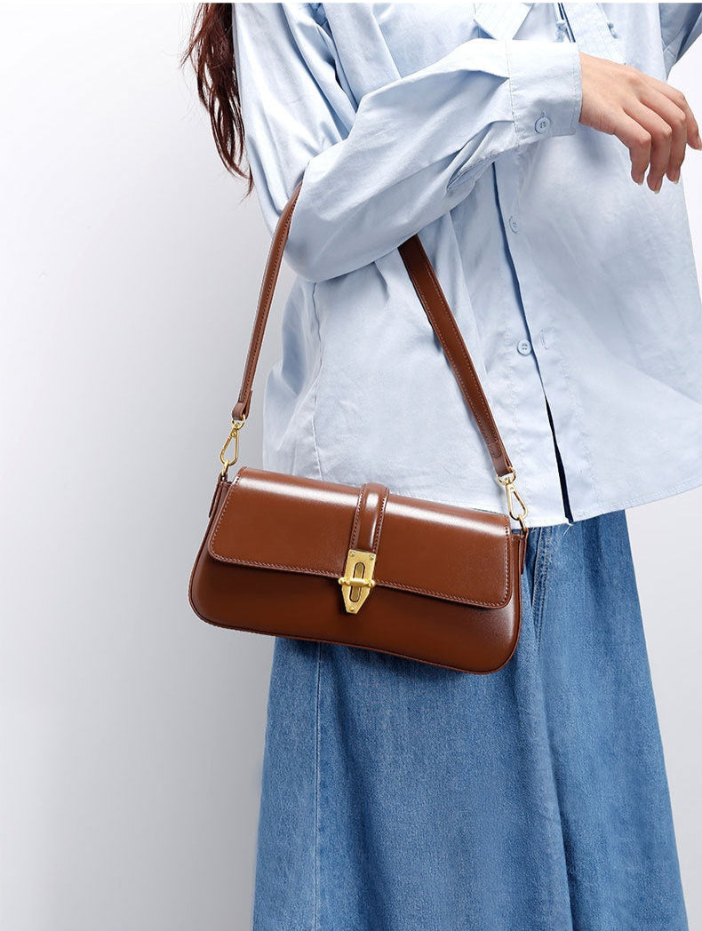 Brown genuine leather handbag carried  by a model wearing a light blue shirt and denim skirt