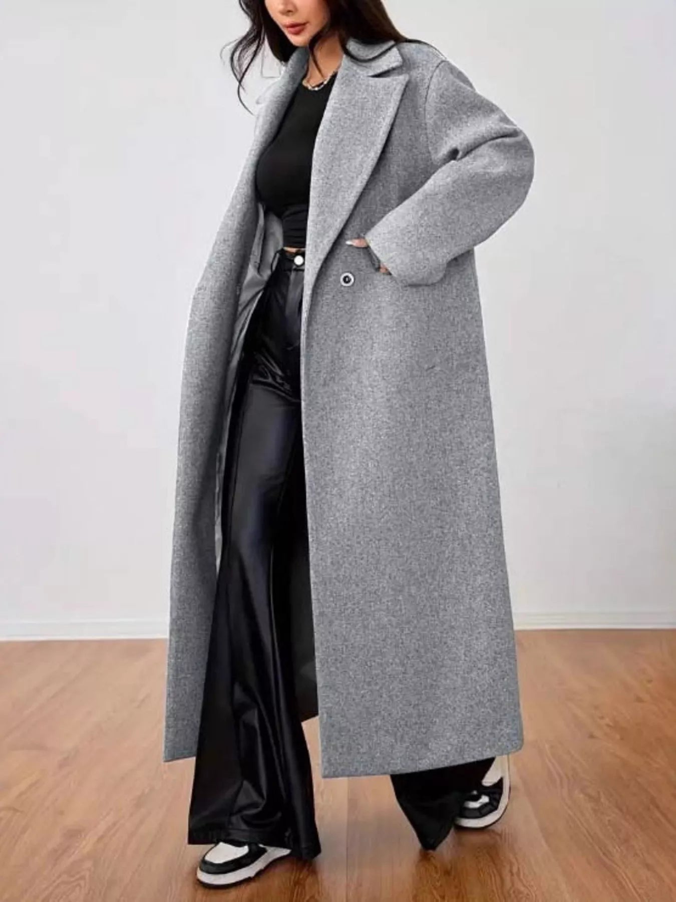 woman wearing a long gray coat over a black outfit side view