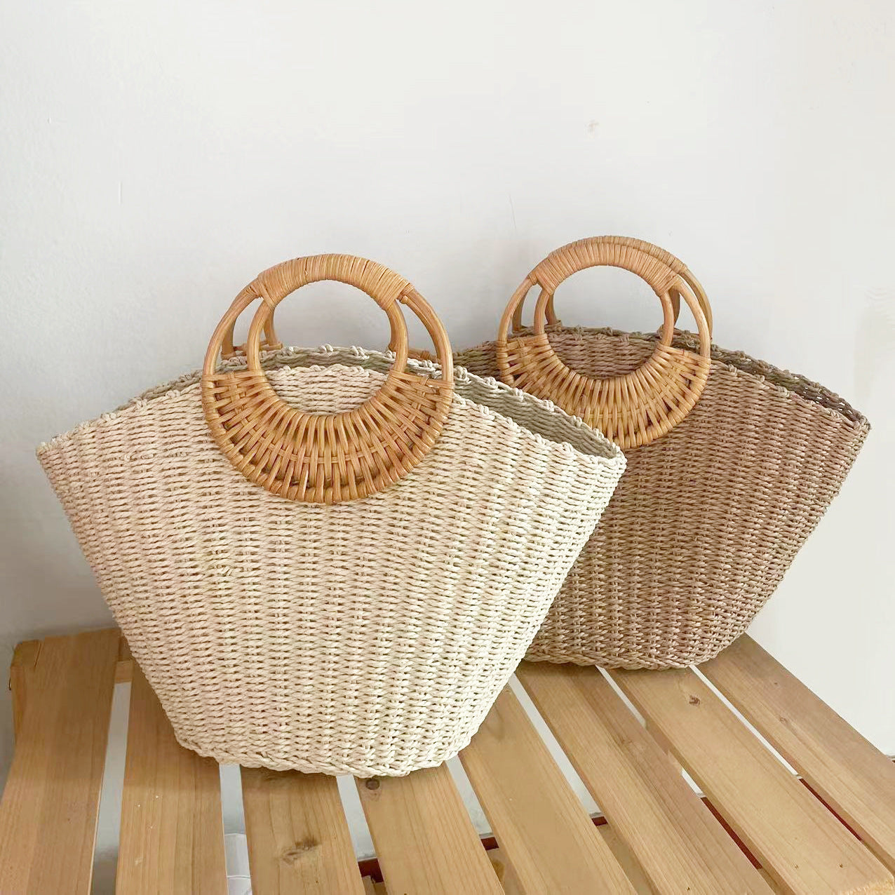Two woven bags with wooden handles on a wooden surface.