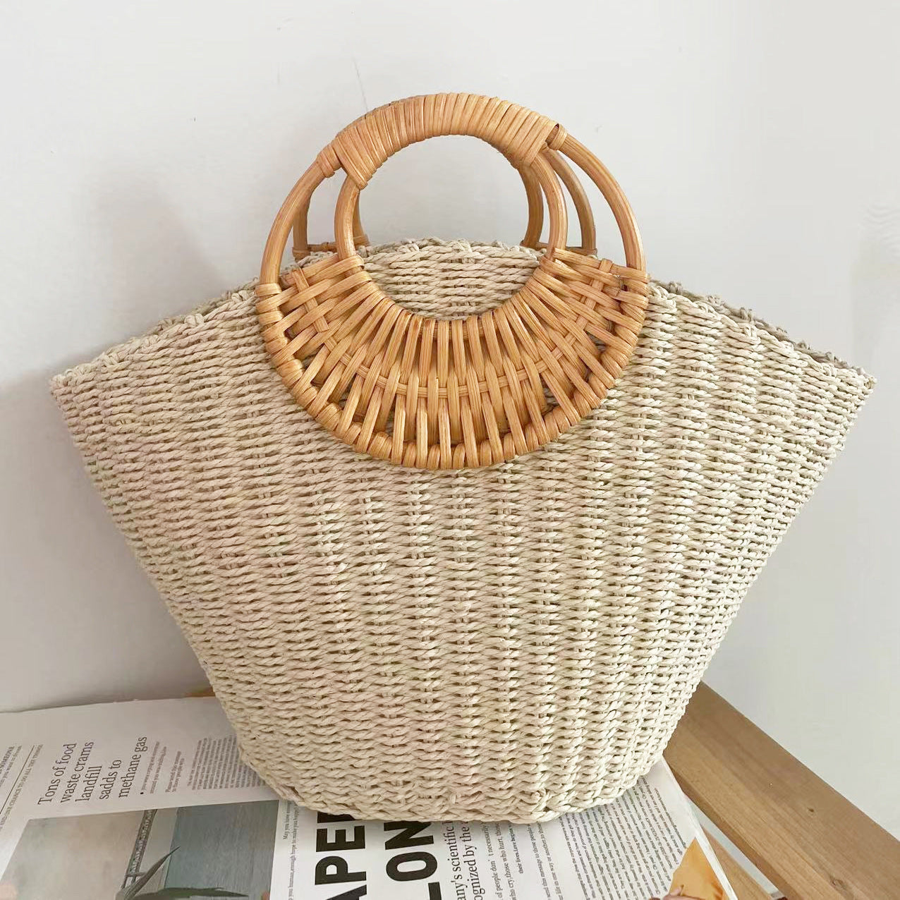 Woven straw bag with wooden handles on a light background