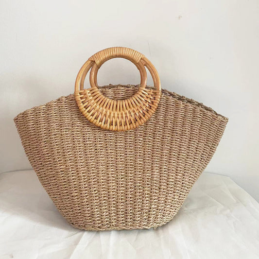 Woven straw handbag with wooden handles on a light background