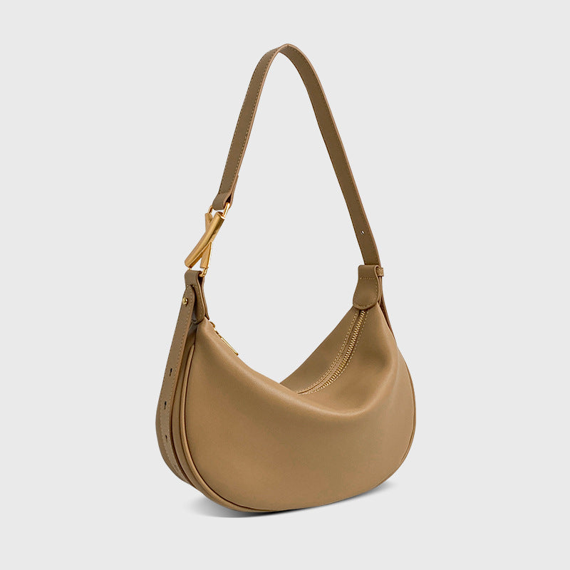 A  tan / apricot crescent-shaped genuine leather handbag with an adjustable strap and a zipper top closure.