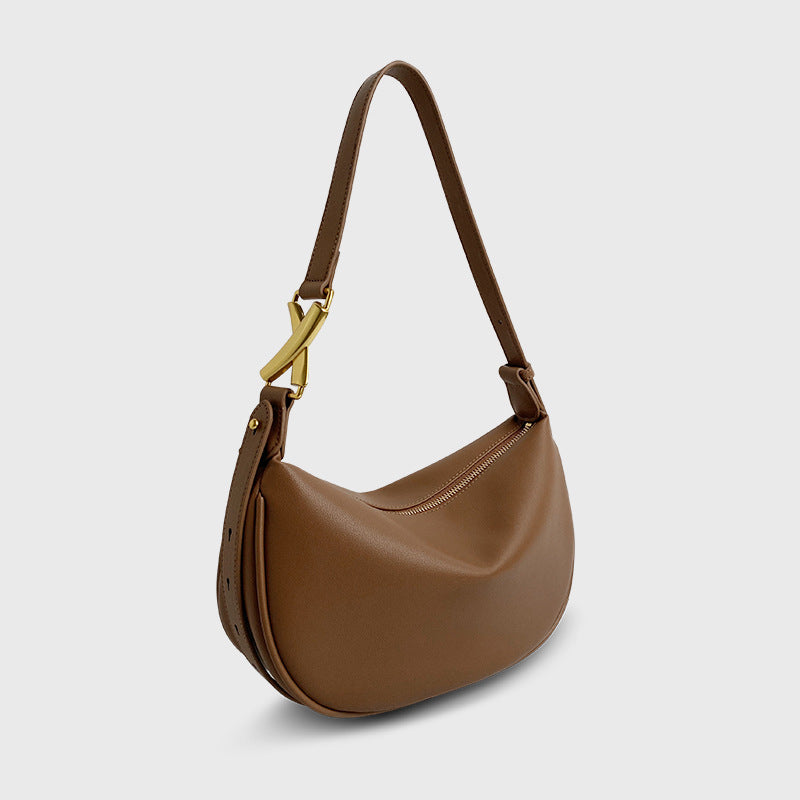 A caramel brown crescent-shaped genuine leather handbag with an adjustable strap and a zipper top closure.