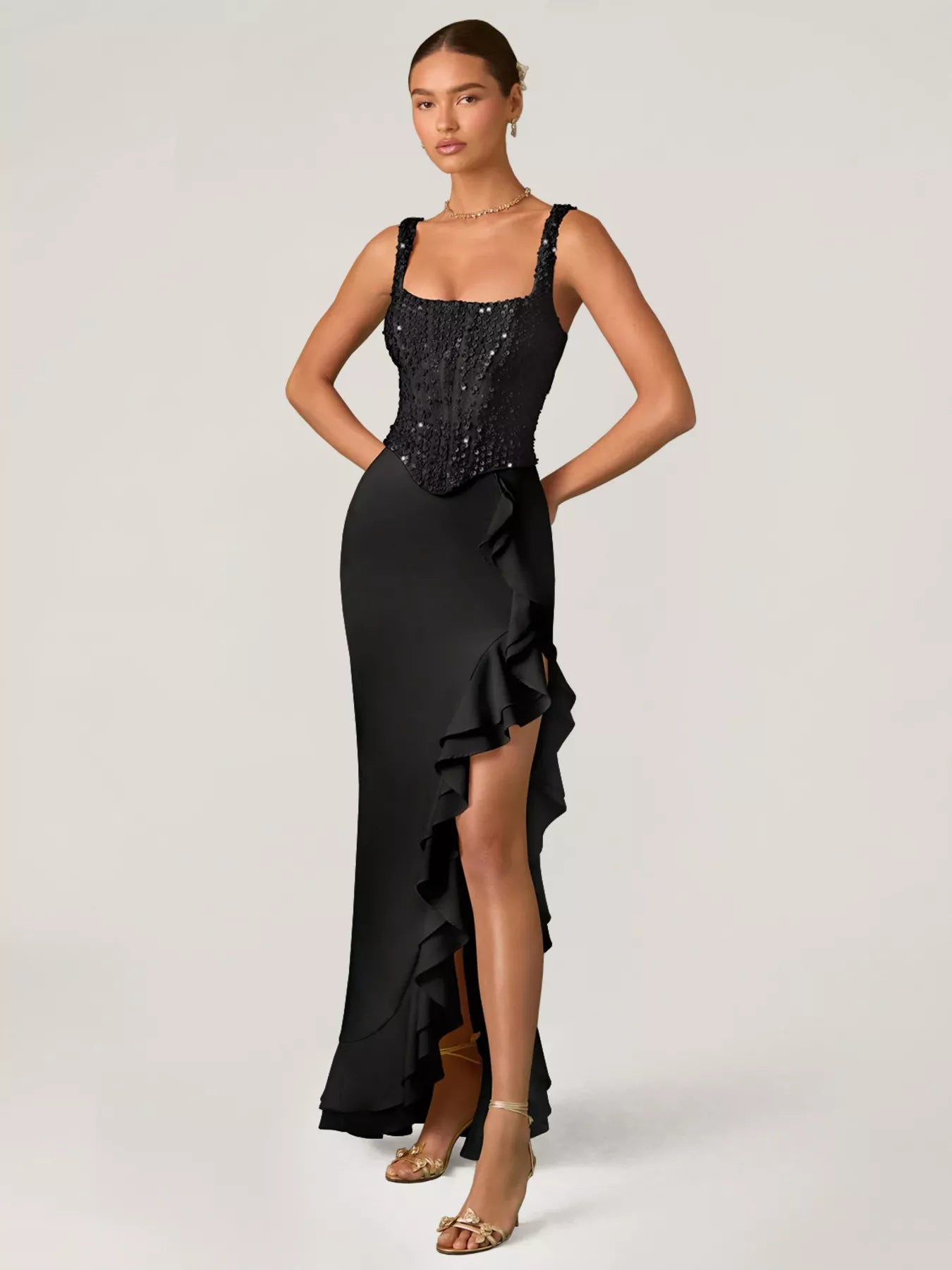 Woman wearing a black gown for occasion wear  with a sequined top on a white background