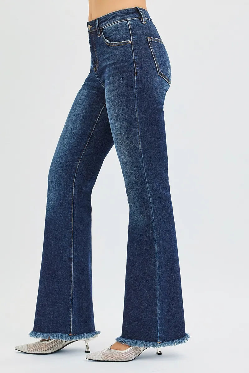 Side view of woman wearing dark wash blue denim mid rise flare leg tummy control jeans 