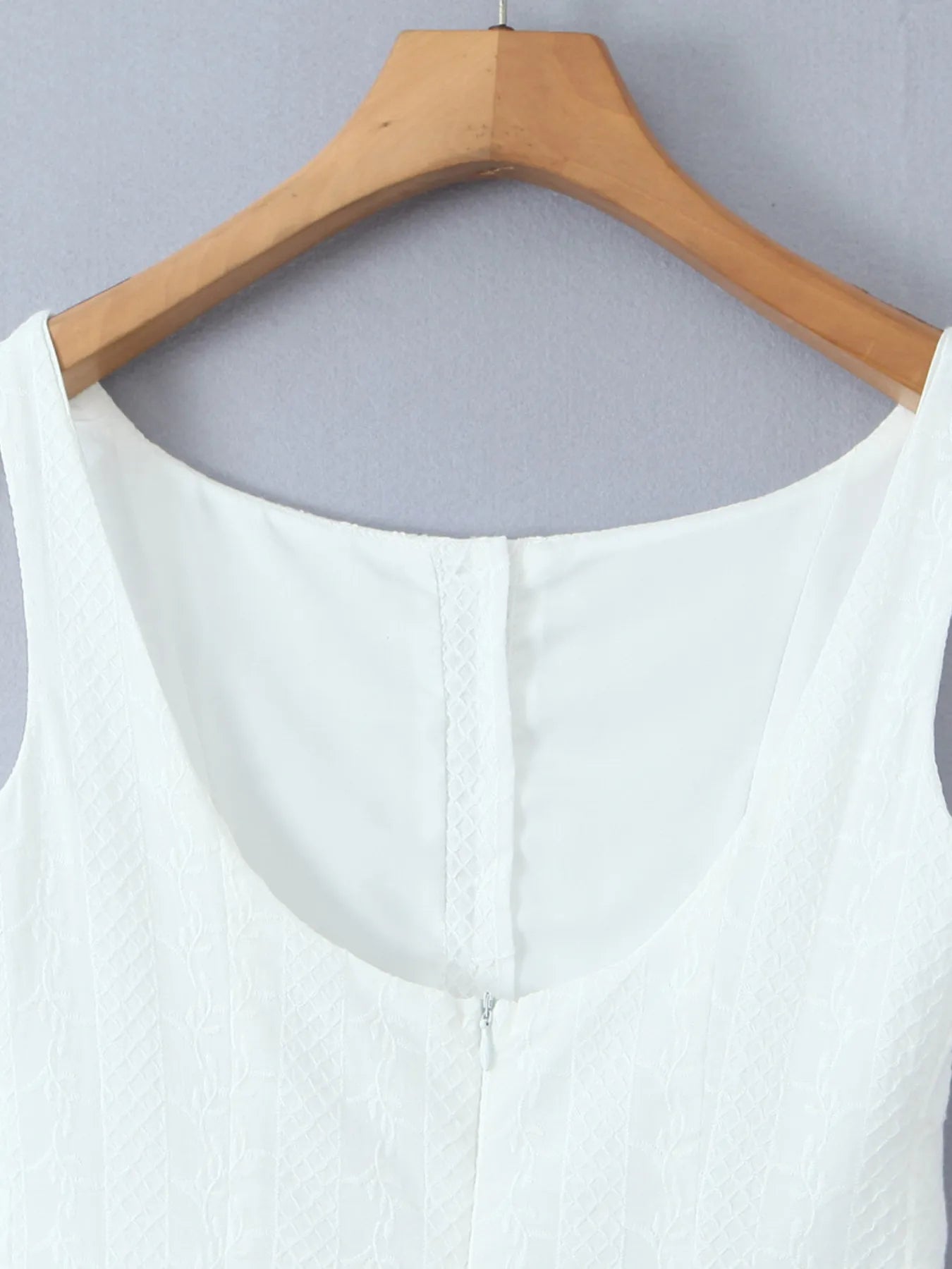 Close-up of lace mini dress in white back view with zipper and fabric texture on hanger