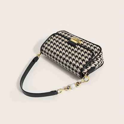 Elegant black and white handbag featuring gold clasp and stylish beaded handle